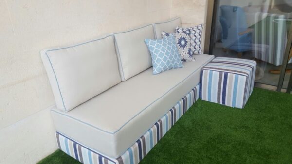 ספה פינתית מעוצבת עם כריות נוי על דשא סינטטי, מתאימה לתאורה לסלון או לגינה.