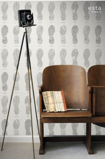 כורסאות עץ ישנות עם ספרים מונחים עליהן ומצלמה ישנה על חצובה, רקע עם טפט דפוס עקבות.