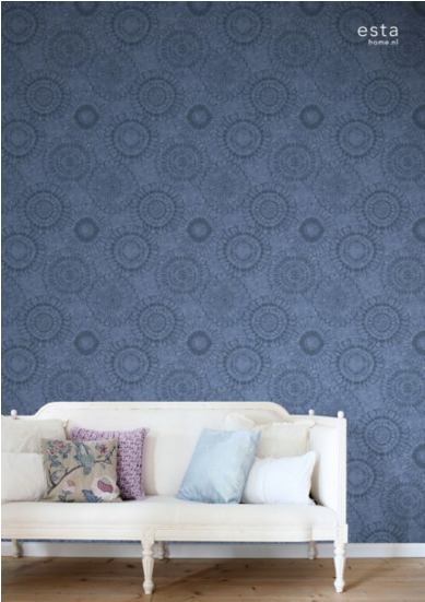 ספה מעוצבת עם כריות נוי מול טפט לקיר בדוגמת מעגלים, תאורה רכה לסלון.