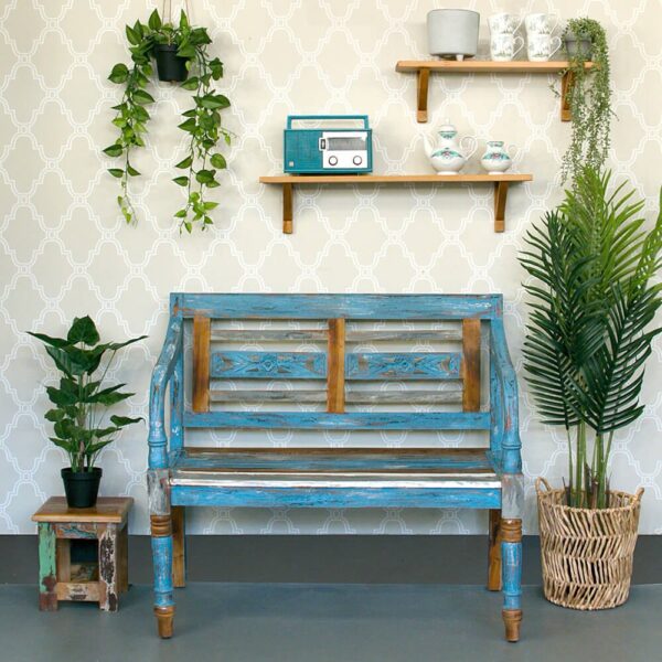 ספה מעוצבת בצבע תכלת עם קירות טפטים, עציצים ומדפים מעץ לשדרוג תאורת סלון.