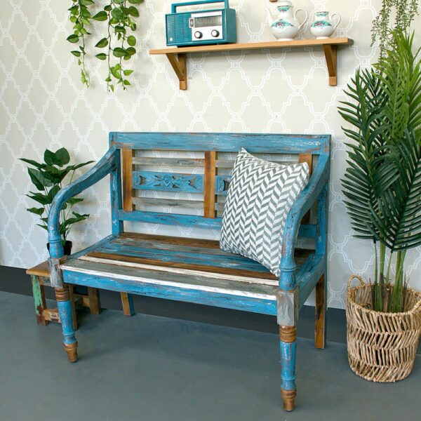 ספה מעוצבת בגוון תכלת עם כרית יפה, בצד צמחייה ועיטורים על הקיר.