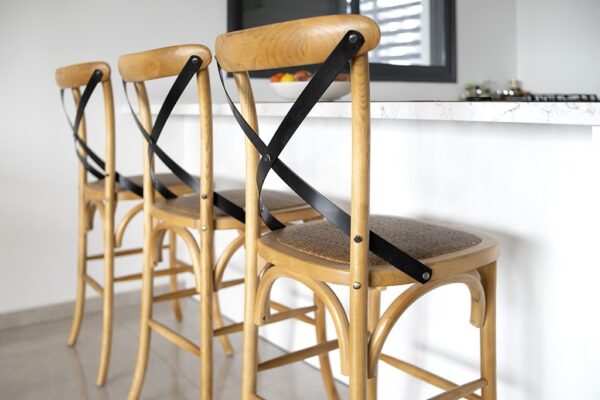 כיסאות בר מעוצבים בעץ עם מושב ארוג, מתאימים לפינת אוכל מודרנית עם תאורה נעימה.